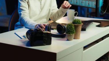 Fotoğraf editörü görüntü ışıklandırması ve renk dengesini düzenliyor, görsel olarak çekici son ürünü sunuyor, müzik dinliyor. Kulaklık takan serbest çalışan, fotoğraflara göz gezdiren, kamera A