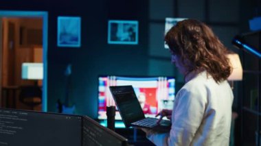 Bilgisayarı kullanarak yazılım hata ayıklama yapan geliştirici, kod satırlarındaki arızaları kontrol eden, hatalara kızan. Kadın evde dolaşıp, not defteri, kamera B kullanarak kodlama sorunlarını düzeltiyor.