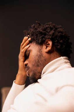 Zor bir günün ardından evde baş ağrısı çeken Afrikalı Amerikalı bir adam endişeli ve stresli hissediyor. Sıkıntılı insan avucunu alnına koyar, acı ve basınç hisseder.