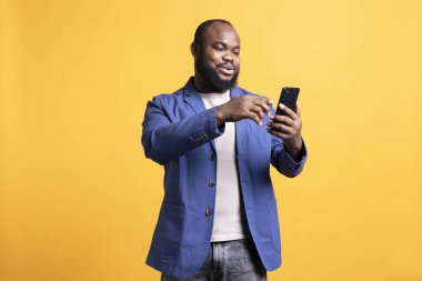 Alışverişkolik Afro-Amerikalı adam akıllı telefondan ödeme metodu ekliyor, stüdyo geçmişi. Gülümseyen BIPOC çalışanı çevrimiçi alışveriş yapıyor, cep telefonuna kredi kartı bilgileri yazıyor