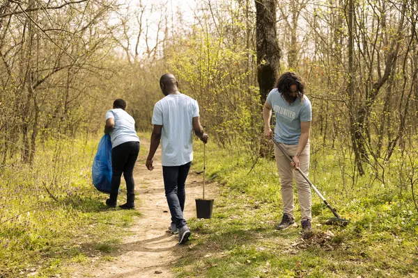 stock image Male environmentalist raking dry leaves to help forest ecosystem restructuration, working in unity to protect the natural habitat. Volunteer takes action for a conservation project.