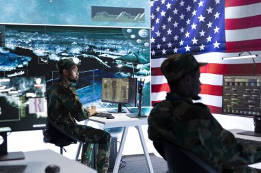 Yüksek teknoloji ofisindeki tehdit tespit faaliyetlerini denetleyen ABD askeri subayı büyük ekrandaki çok gizli verileri inceliyor. Amerikan askerleri hibrit savaşı yönetiyor, siber saldırı önleniyor.