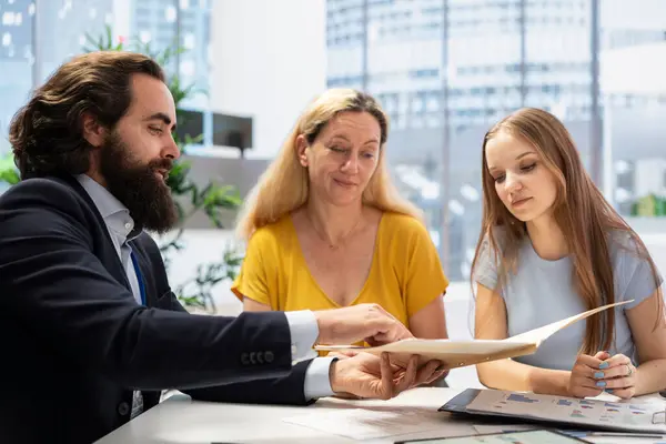 stock image Portfolio Manager in office analyzing economic reports, developing investment objectives and talking with customers. Financial advisor helping family wanting to purchase house