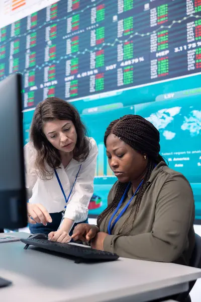 stock image Diverse team of analysts examining monthly cost and revenue elements on a big screen, working on creating a financial projection for future improvements and success within the organization.