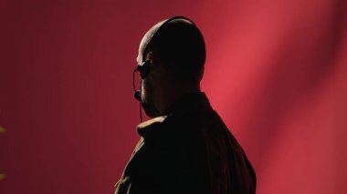 Askeri sevkiyat subayı savaş cephelerindeki askerlere bilgi sağlıyor, mikrofonla konuşuyor. Üniformalı telsiz iletişim operatörü birlikleri koordine ediyor, kamera A