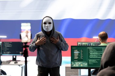 Anonymous hacker expert in a russian hacking high tech office, digital threats and political espionage. Inflicting cyber terror, propaganda and crisis management in information war. clipart