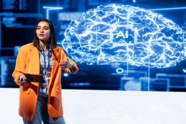 Bilgisayar bilimcisi yapay zeka zirvesinde sunum yapıyor. Tablet kullanarak profesyonelleri topluyor. Teknisyen yapay zekanın yenilikleri nasıl zorladığını göstermek için aygıt kullanıyor.