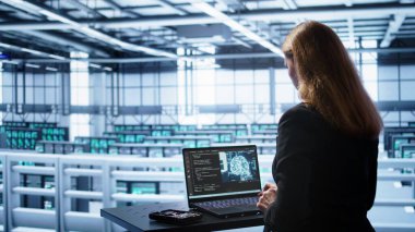 Veri merkezinde mühendis yapay zeka kullanarak bilgisayarlı modeldeki insan beyni düşünce süreçlerini simule ediyor. Çalışan, yapay zeka öğrenme algoritmaları ve B kamerasıyla dizüstü bilgisayarda çalışır.