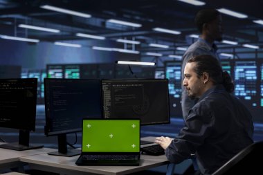 Veri merkezindeki yönetici sunucu performans sorunlarını kontrol etmek için izole ekran laptopu kullanıyor. Bilgi işlem uzmanı sunucu merkezi düzeltme hataları donanımı krom anahtar not defteri kullanarak yavaşlatıyor
