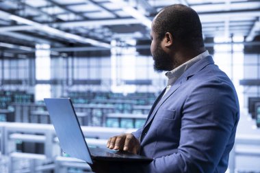 Veri merkezindeki programcı, laptop kullanarak altyapı veri kaybından korunmak için yedek çözümler uyguluyor. Modern iş yeri IT profesyonel sorunları dizüstü bilgisayarla çözülüyor