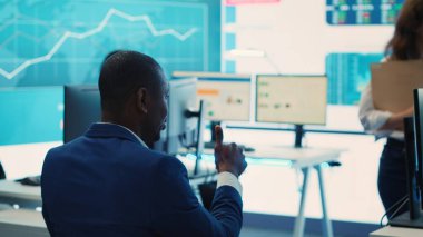 İdari danışman, iş hedeflerine ulaşmak ve küresel ölçekte genişlemek için iş akışını iyileştirmenin yollarını arayarak, performans ölçümleri hakkında görüşmek üzere personelini bir araya getiriyor. Kamera A.