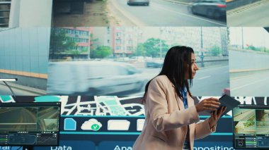 Hintli yönetici uydu haritası üzerinden cadde trafiğini takip ederek kargo teslimat lojistiği hakkında istihbarat topluyor. Müdür kontrol merkezinde ekibiyle birlikte çalışıyor. Kamera B.