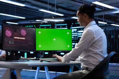 Sunucu merkezinde bilgisayar kullanarak donanımı hackerdan korumaya çalışan bir bilgisayar uzmanı. Yüksek teknoloji veri merkezi işyerindeki siber güvenlik uzmanı yeşil ekrandaki güvenlik ihlalini düzeltmeye çalışıyor.