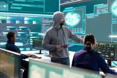 Hükümet hackerları siber tehdit tespiti için verileri analiz ediyor, yüksek teknoloji ofisindeki büyük ekrana bakıyor. Siber istihbaratı, çevrimiçi güvenliği ve dijital tehditlerin önlenmesini vurgula.