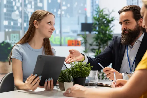 stock image Young adult reading files on tablet given by student loan advisor in office assisting her fix financial troubles. Student visiting counselor with her mother to ask for help managing payments