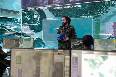 Özel harekat mühendisi büyük ekranda GPS izleme sistemi olan bir dünya haritasını inceliyor. İzleme odasının güç üssünde askeri yüksek teknoloji donanımı kullanılıyor. Hükümet uydusunu görevler için çalıştırır.