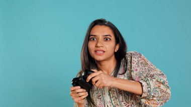 Neşeli oyuncu oyun konsolunda kazandıktan sonra kutlama yapıyor, stüdyo arka planında. Video oyununda zafer kazandıktan sonra övünen Hintli kadın tüm düşmanlarını oyun sahası B kamerasıyla yeniyor.