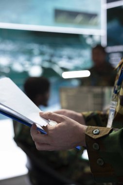 Görevli, çok gizli dava dosyasındaki özel operasyon detaylarını inceliyor. Savunma görevinin başarıya ulaşmasını sağlamak için önemli savaş alanı bilgilerini okuyor. Trooper komuta merkezinde çalışıyor. Kapat..