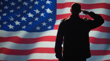 Soldier saluting USA flag, participating in 4th of July celebrations. United States of America veteran honoring country during memorial day event, doing patriotic hand gesture towards flag, camera B clipart