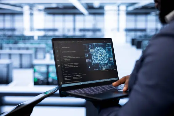 stock image System administrator in data center using laptop to visualize artificial intelligence neural networks made up of interconnected nodes. Close up of employee oversees AI systems processing information