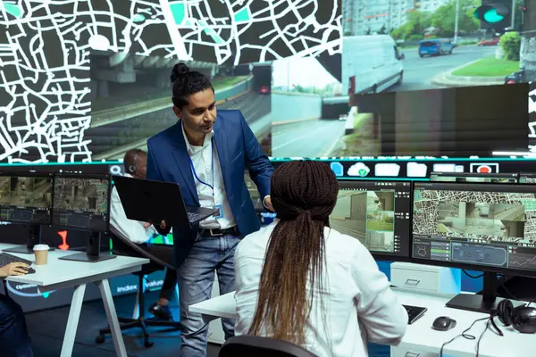 stock image Indian man instructing his employees in using CCTV surveillance system to help couriers with directions and gps coordinates. Shipping agency working on express delivery service, satellite map.