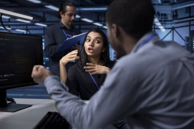 Bilgi işlem personeli sunucu odasında potansiyel tehditlerden korunan verileri sağlıyor. Veri merkezi donanımını kötü amaçlı yazılıma karşı korurken iş yerinde sohbet eden çok ırklı iş arkadaşları