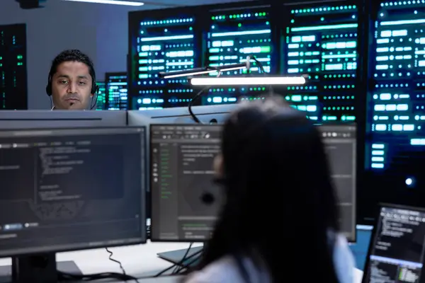 stock image Team of professionals in data center supporting engineering team doing equipment maintenance, talking in headset microphone. Teamworking colleagues in server farm coordinating technicians using mic