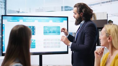 Şirket finans departmanındaki takım lideri yatırım varlıklarının toplandığı büyük ekranda hisse senedi portföyünü gösteriyor. Büyük ekranda hisse senedi talebi artışı gösteren işadamı, kamera A