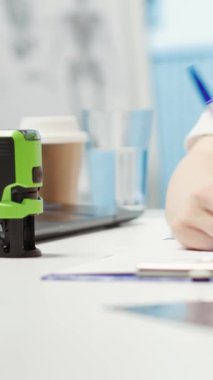 Dikey Video Genel Pratisyeni hastası için reçeteli bir belgeye damgasını basıyor. Tıbbi tedavi olarak antibiyotik ve vitamin öneriyor. Doktor kabinede ilaç yazıyor.