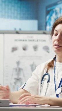 Dikey Video Uzmanı tavsiye edilen antibiyotiklerle reçeteli ilaç yazıyor ve hastalara talimatlar veriyor. Sağlık sigortası için reçeteli tedavi hapları