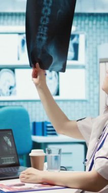 Dikey Video Sağlık Uzmanı, tıbbi uzmanlığını ofisteki bir hastayla paylaşıyor, röntgen ve MRI taramalarını inceliyor ve doğru tanı ve hasta bakımına odaklanıyor. Tıbbi hizmetler