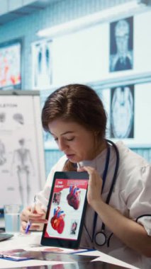 Dikey Görüntü Sağlığı Sağlayıcı Kardiyoloğu kalp fonksiyonlarını bir kardiyogramda açıklıyor, bir tıp ofisinde doktor hasta etkileşimi. Olası durumu vurgulayan sağlık görevlisi, kardiyovasküler