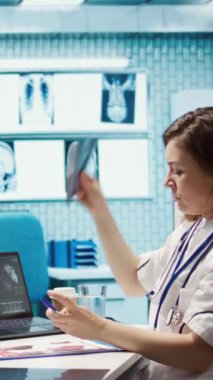 Dikey Video Medikal personeli teşhis raporlarını inceliyor ve röntgen görüntüleme ve tarama yorumlarına odaklanıyor. Modern sağlık muayenesi ve klinikte hasta teşhisi