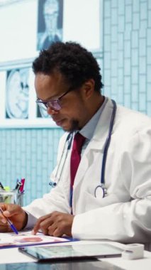 Dikey Video Erkek Hekimi, muayene sırasında röntgen taraması yaparak kabinedeki iyileşme tedavisini tartışıyor. Radyografi testinin sonuçlarını inceleyen doktor...