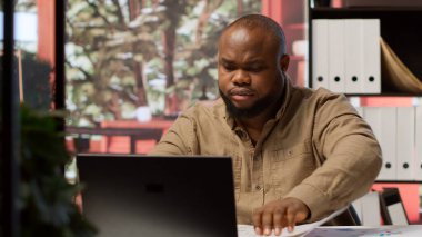 Ofis kiralama için araştırma ve istişare yürüten işadamı, stratejik bir yatırımı güvence altına almak için planlar ve mimari planların değerlendirilmesi. Ofis avı geliştirme. Kamera A.