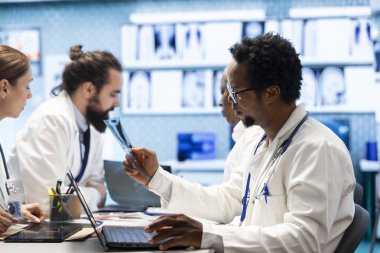 Çeşitli doktorlar kabinedeki tedavi hizmetlerini tartışıyorlar. Etkili tedavi planları ve uzmanlık geliştirmek için x-ray sonuçlarını ve hastane kayıtlarını inceleyen lisanslı doktorlar..