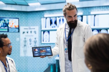 Nöroloji uzmanları, tomografi test sonuçlarına dayanan potansiyel hastalıkları tartışmak üzere kabinede MRI beyin taramasını incelemek için toplandılar. Uzman ekip hastane kayıtlarını inceliyor..