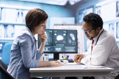 Genel pratisyen bir hasta için oksijen doygunluğunu ve hayati belirtileri ölçer ve kabine ofisindeki diğer teşhis araçlarını kullanır. Erkek uzman bir kadına danışmanlık yapıyor, sağlık hizmetleri..