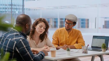 Modern çalışma alanı tasarımını değerlendiren ve yatırım stratejilerini ve kiralama seçeneklerini tartışan bir ofis turundaki müşteriler ve emlakçılar. Planları gözden geçiriyorum ve ofisin yerini değiştiriyorum. Kamera B.