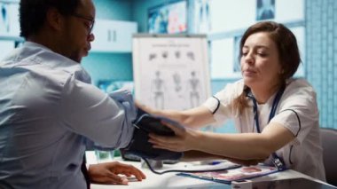 Hasta için kan basıncı ve nabız ölçen kadın doktor, kan basıncı monitörü ve diğer teşhis aletleriyle çalışıyor. Profesyonel kardiyoloji sınavı, yüksek kaliteli okumalar. Kamera B.