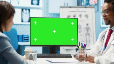 Genel pratisyen hekim, izole edilmiş kroma anahtar görüntüsünün yanındaki kadın hastaya danışarak laboratuvar sonuçları ve analizleri hakkında bilgi paylaşıyor. Becerikli sıhhiyeci müşterisini destekliyor, içeride kontrol ediyor. Kamera A.