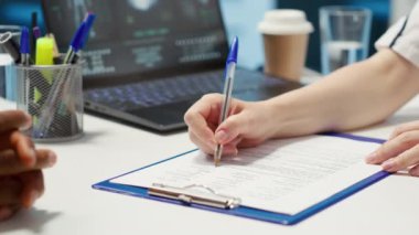 Kadın doktor, en iyi ilaç ve ağrı kesicileri hastaya veren reçeteli bir belgenin tıbbi talimatlarını ve dozajını belirtiyor. Ofiste sağlık hizmeti danışmanlığı. Kamera A.