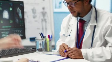 Doktor, tıbbi reçeteyle verilen vitamin ve ağrı kesicilerin dozajını belirterek, talimatları ve çabucak iyileşme sürecini açıklıyor. Modern sağlık hizmetleri. Kamera A.