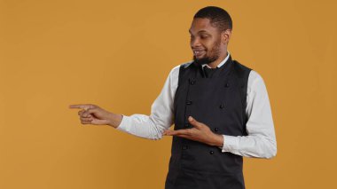 Profesyonel üniformalı garson, sağa ya da sola bir şey gösteriyor. Beş yıldızlı restoran reklamı yapıyor. Konukseverlik sektöründe yemek servisi. Kamera B.