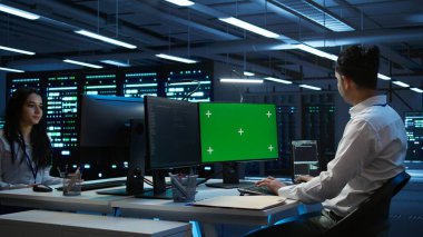 Veri merkezindeki programcı veri tabanlarını kontrol ediyor ve koruyor. Model PC kullanarak, veri bütünlüğü ve güvenliğini sağlıyor. Yeşil ekran bilgisayar kullanarak sunucu odası sistemleri güncelleme uzmanı, kamera B