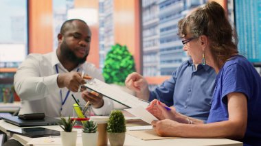 Üst düzey müşteriler finansal danışmana çeşitli emeklilik seçenekleri hakkında soru sorarak, gelecekteki istikrar için birikimlerini ve emeklilik maaşlarını koruyorlar. Gelirlerini artırmak için danışmanlık. Kamera A.