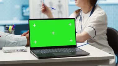 Pratisyen hekim ve hasta kontrol sırasında yeşil ekrana bakıyor, ilaç ve ilaç öneriyor. Çeşitli insanlar tanı ve tedaviyi tartışıyor. Kamera A.