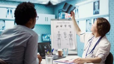 Bir hastanın teşhis raporlarını ve sonuçlarını inceleyen tıbbi personel röntgen görüntüleme ve tarama yorumlarına odaklanıyor. Modern sağlık muayenesi ve klinikte hasta teşhisi. Kamera B.
