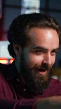 Video çekmek için akıllı telefonu selfie çubuğunda kullanan, çılgın hareketler yapan dikey videolu adam. Stüdyoda telefonla video bloğu çekerken hareketli el hareketleri yapan canlandırıcı, kamera