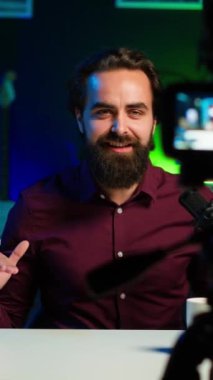 Dikey video iyimser içerik yaratıcısı rgb lights stüdyosunda online şov sunuyor profesyonel mikrofon kullanarak vlog çekiyor. Canlı yayın sırasında bilgilendirme sunan neşeli vlogger
